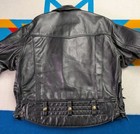 Black vintage leather Langlitz motorcycle jacket with gold studs, snap buttons, and quilted back panel on blue background.