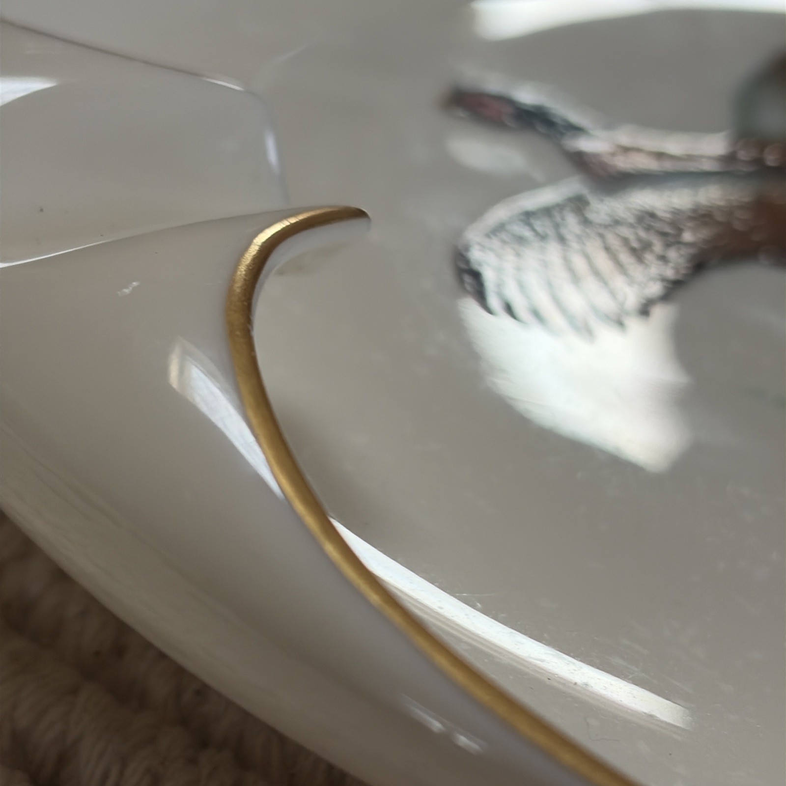 White porcelain ashtray with gold rim and central cigarette rest, made in the USA.