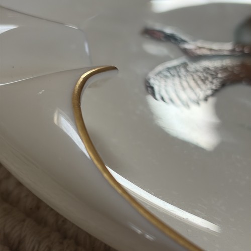 White porcelain ashtray with gold rim and central cigarette rest, made in the USA.