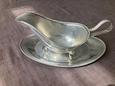 Silver plated sauce/gravy boat on three feet together with a saucer.