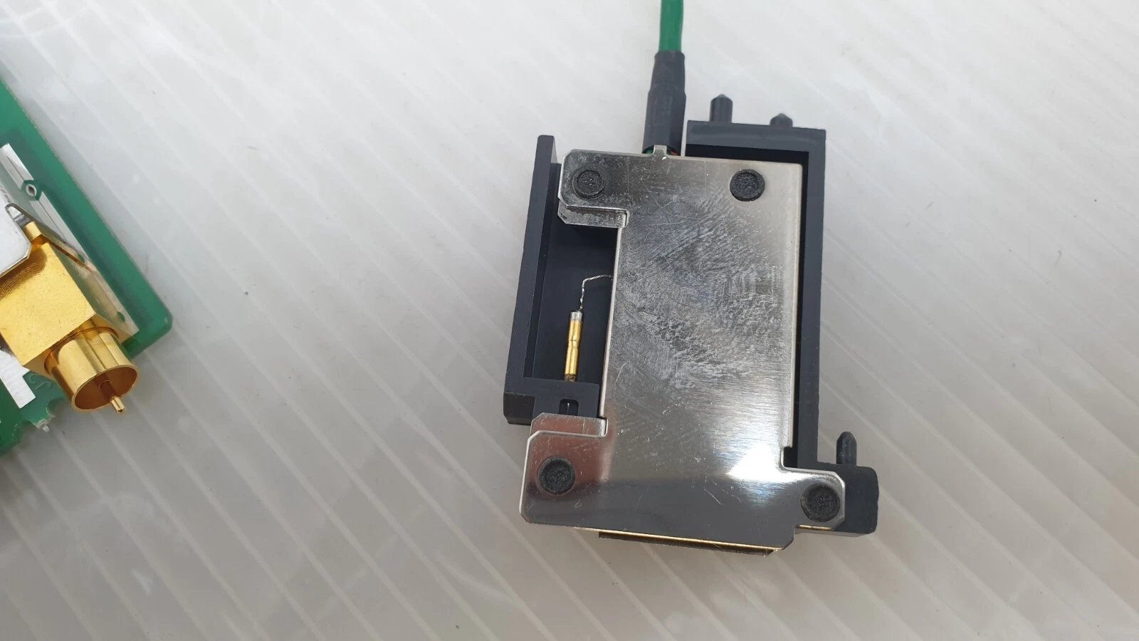 Black connector housing with metal cover and gold contact on the green lead