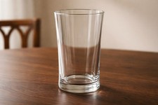 Clear cylindrical glass vase with tapered top and thick base.