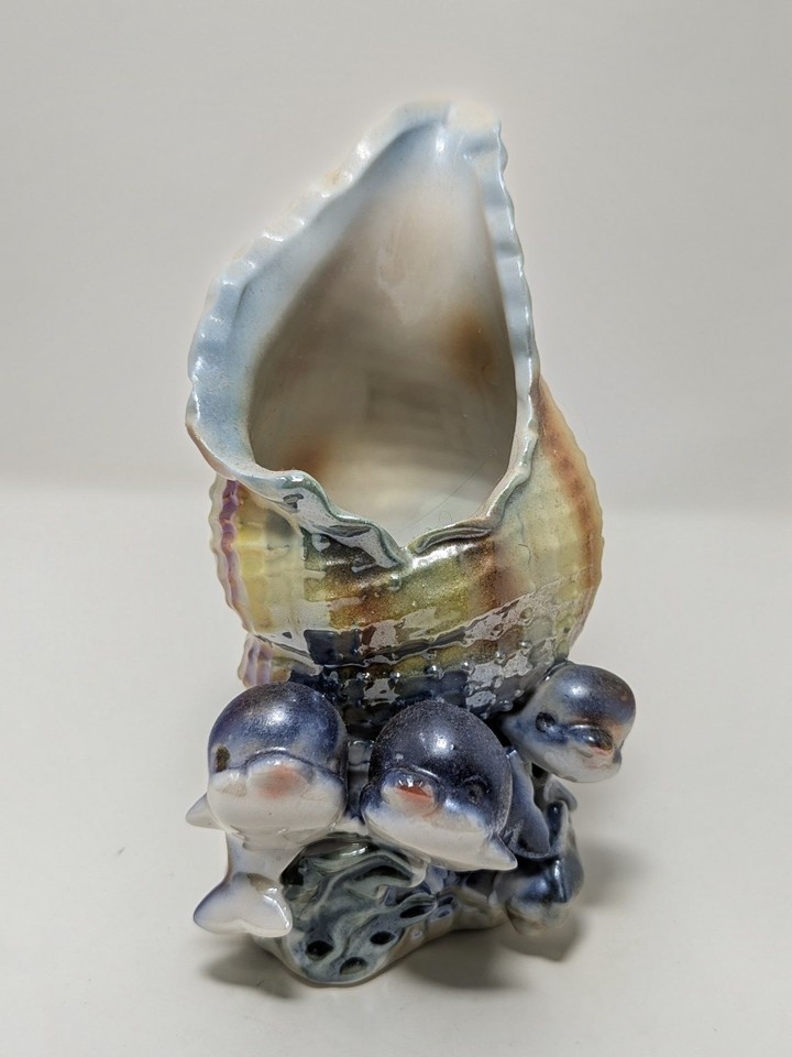 A lustreware dolphin-trio seashell dish is exactly the kind of gloriously over-the-top vintage coastal kitsch that commands a shelf of its own.