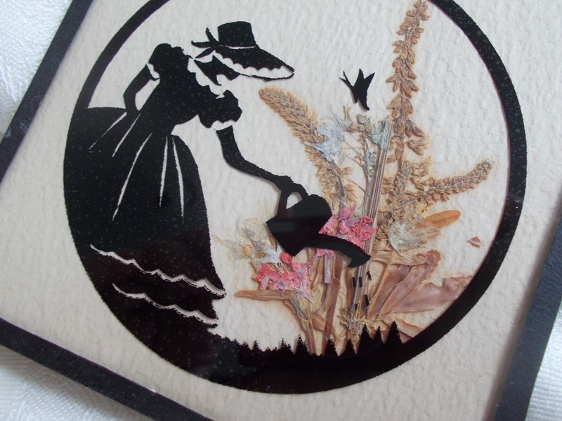 Antique hand-cut paper figure + dried flower silhouette under glass