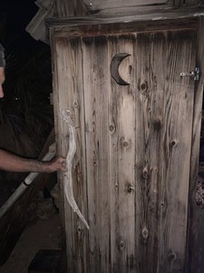 antique reclaimed wood outhouse/toolshed  with crescent moon cutout on door