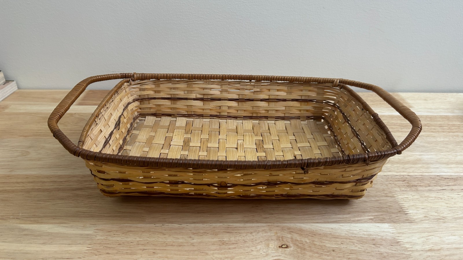 Rectangular hand-woven rattan serving tray with wooden handles.