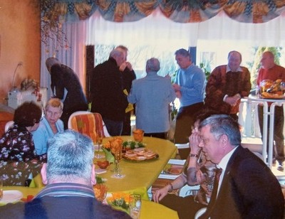 Frauen und Männer sitzen an gedecktem Tisch im Wohnzimmer Familie Feier Farbfoto