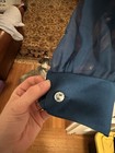Hand holding a navy blue fabric pouch with silver sequin, attached to a sheer dark blue garment, indoors near a dog.