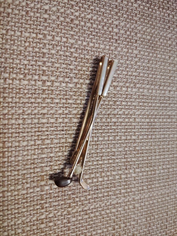 A gold-tone Swank tie bar shaped like crossed golf clubs — exactly the kind of witty, wearable vintage menswear detail that elevates a gift from forgettable to charming.