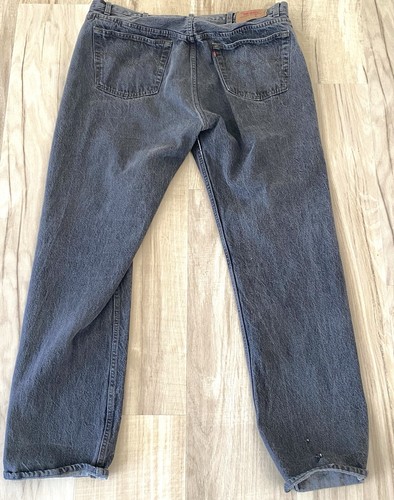 Black Levi’s 501 XX with button fly, two back pockets, and visible yellow stitching on waistband and legs.