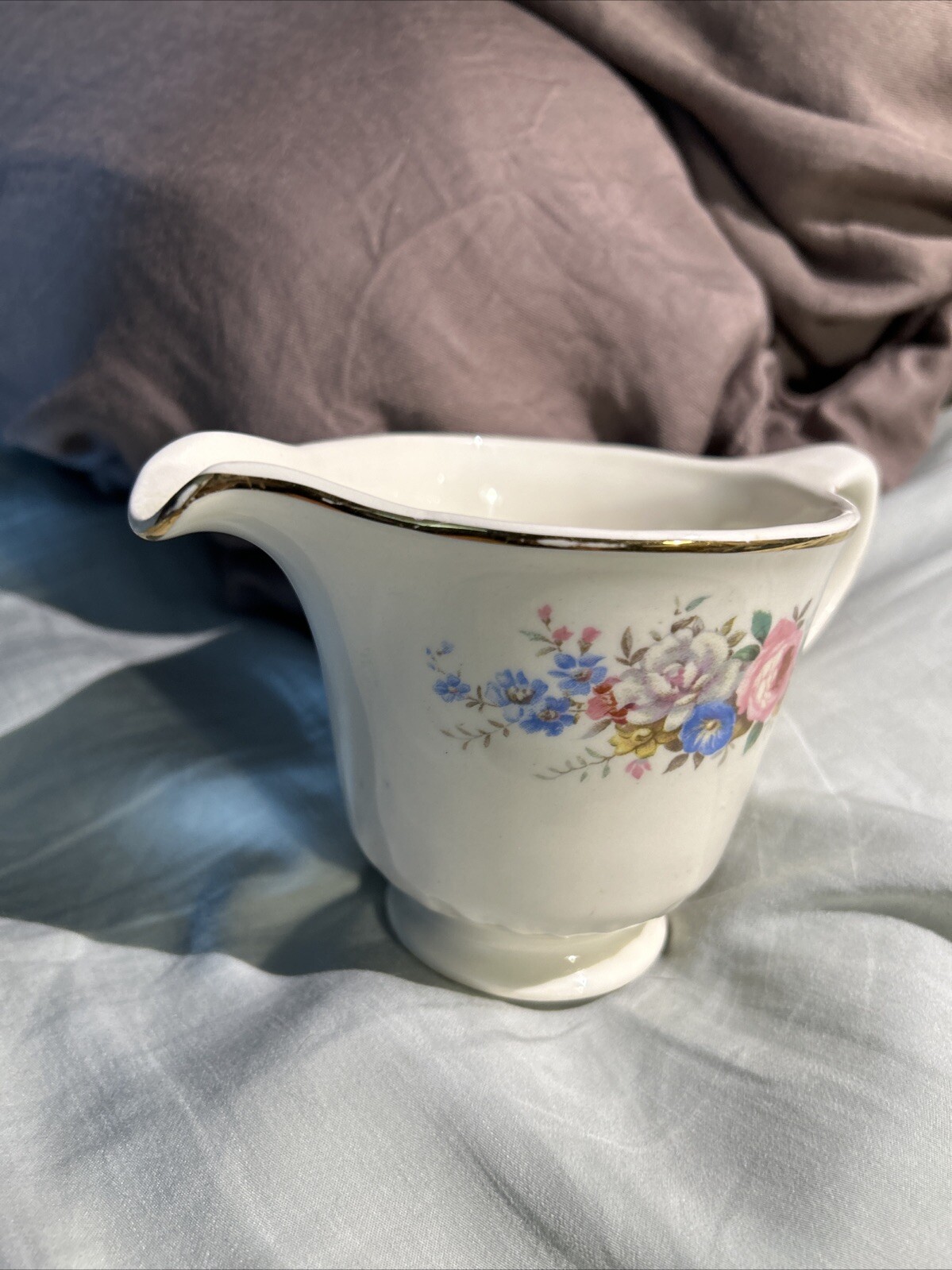 White ceramic pitcher with gold rim, pink and blue floral print, and “Made in U.S.A.” text on body.