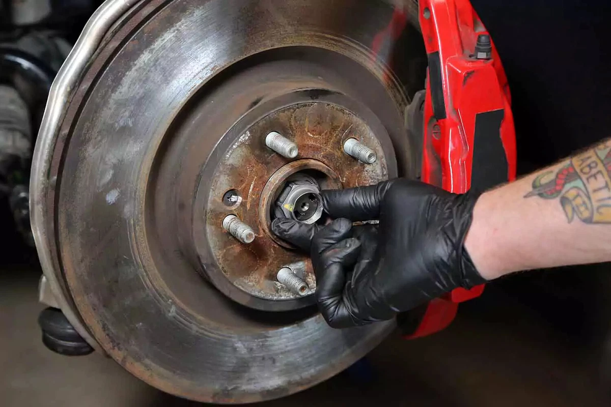 A mechanic reinstalls the axle nut, threading it by hand.