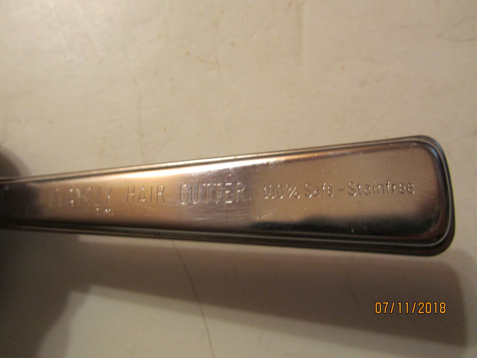 Vintage silver Playtex Hair Cutter with black handle, engraved “100% Safe-Stainfree” beside engraved “7/11/2018.”