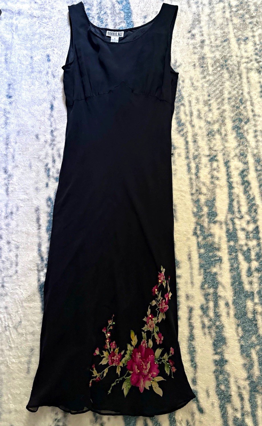 Black chiffon slip dress with an embroidered floral applique at the hem