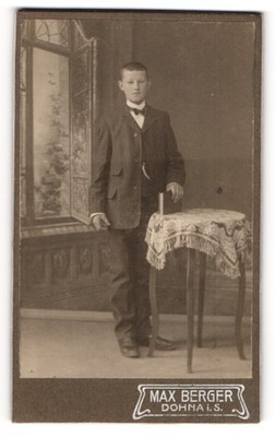 Fotografie Max Berger, Dohna i. S., junger Knabe im Anzug zur Kommunion vor ein 
