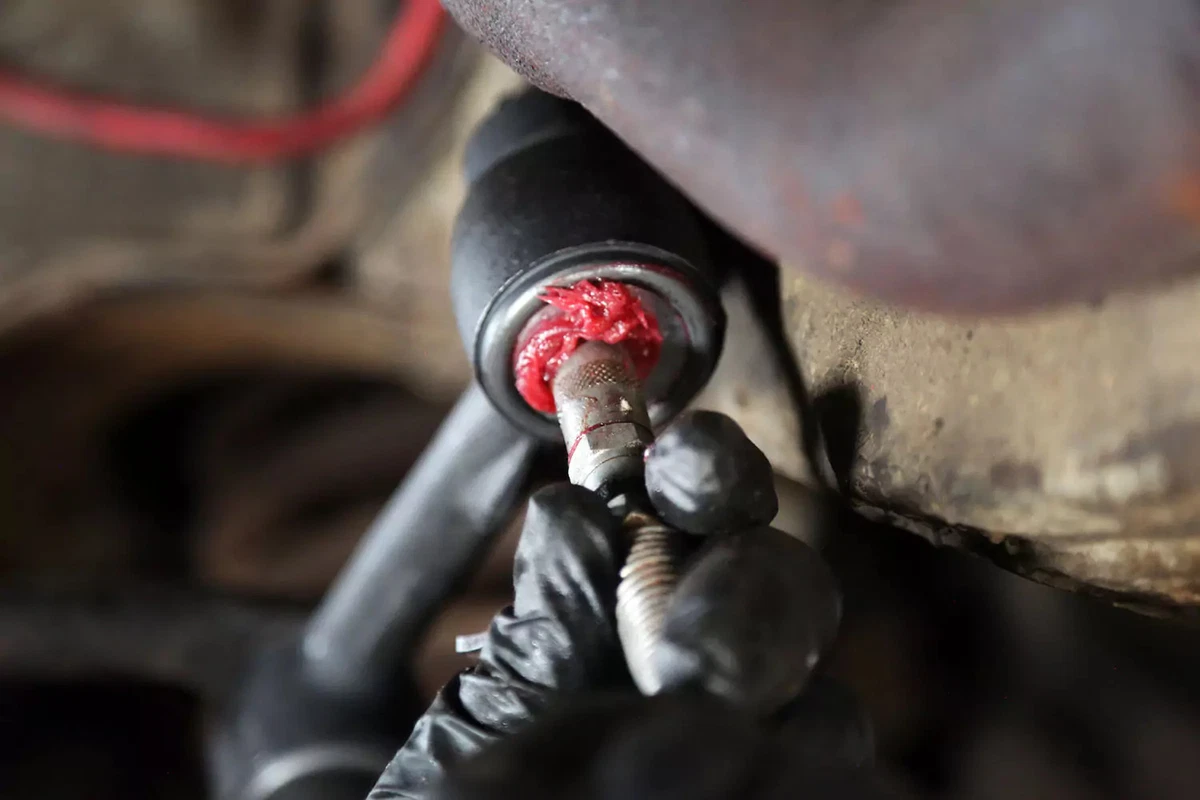 Filling the idler arm ball joint with fresh grease.