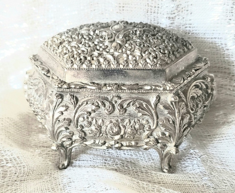 A silvertone ornate music box playing 'It's a Small World' — tiny, melodic, and dripping with mid-century trinket-box elegance.
