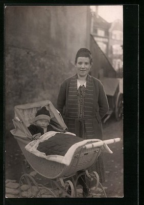 Photo postcard young mother with toddler in pram in front of a house wall 