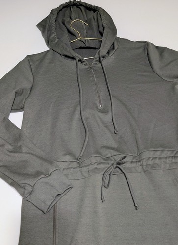 Olive women's hoodie with long sleeves, front zipper, elastic cuffs, and gathered waist, hanging on a wooden hanger.