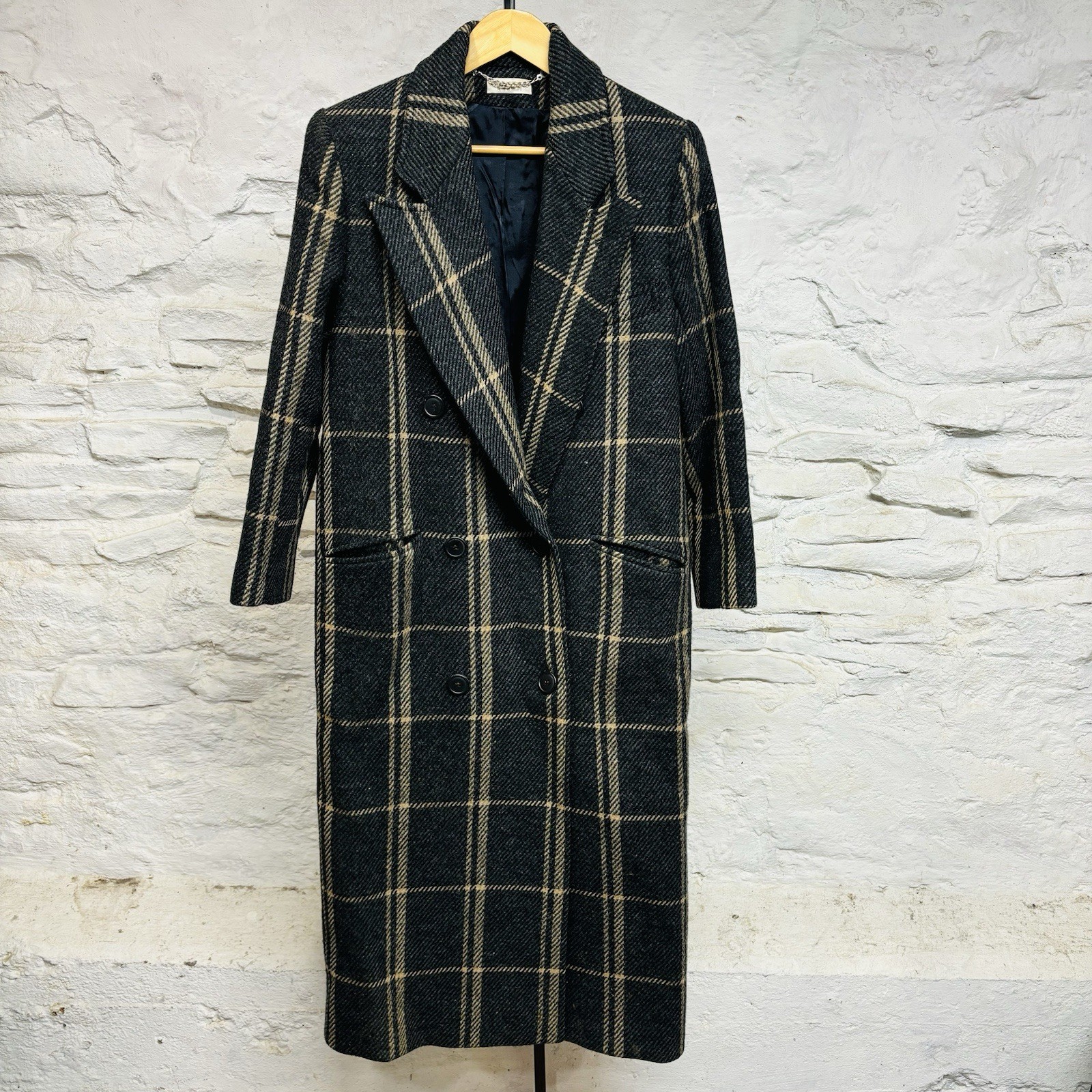Charcoal and tan windowpane plaid wool trench coat on a hanger, front view