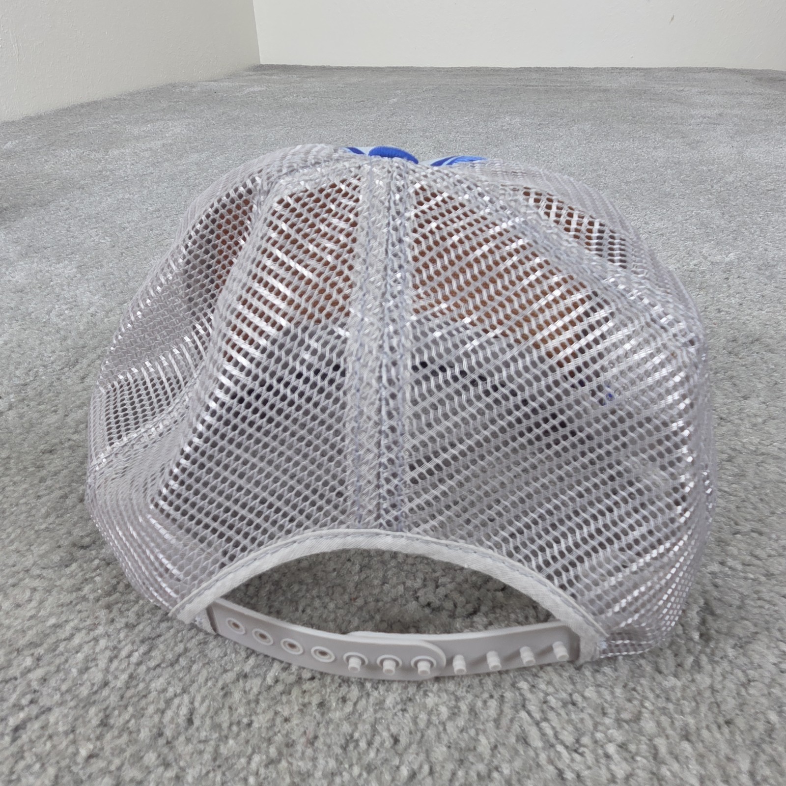 Gray US Air Force Indian Chief trucker hat with mesh back and silver mounting hardware on a gray carpet surface.
