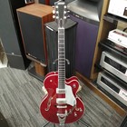 GRETSCH G6119 TENNESSEE ROSE full-body electric guitar with silver hardware and three pickups, displayed on a wooden stand.