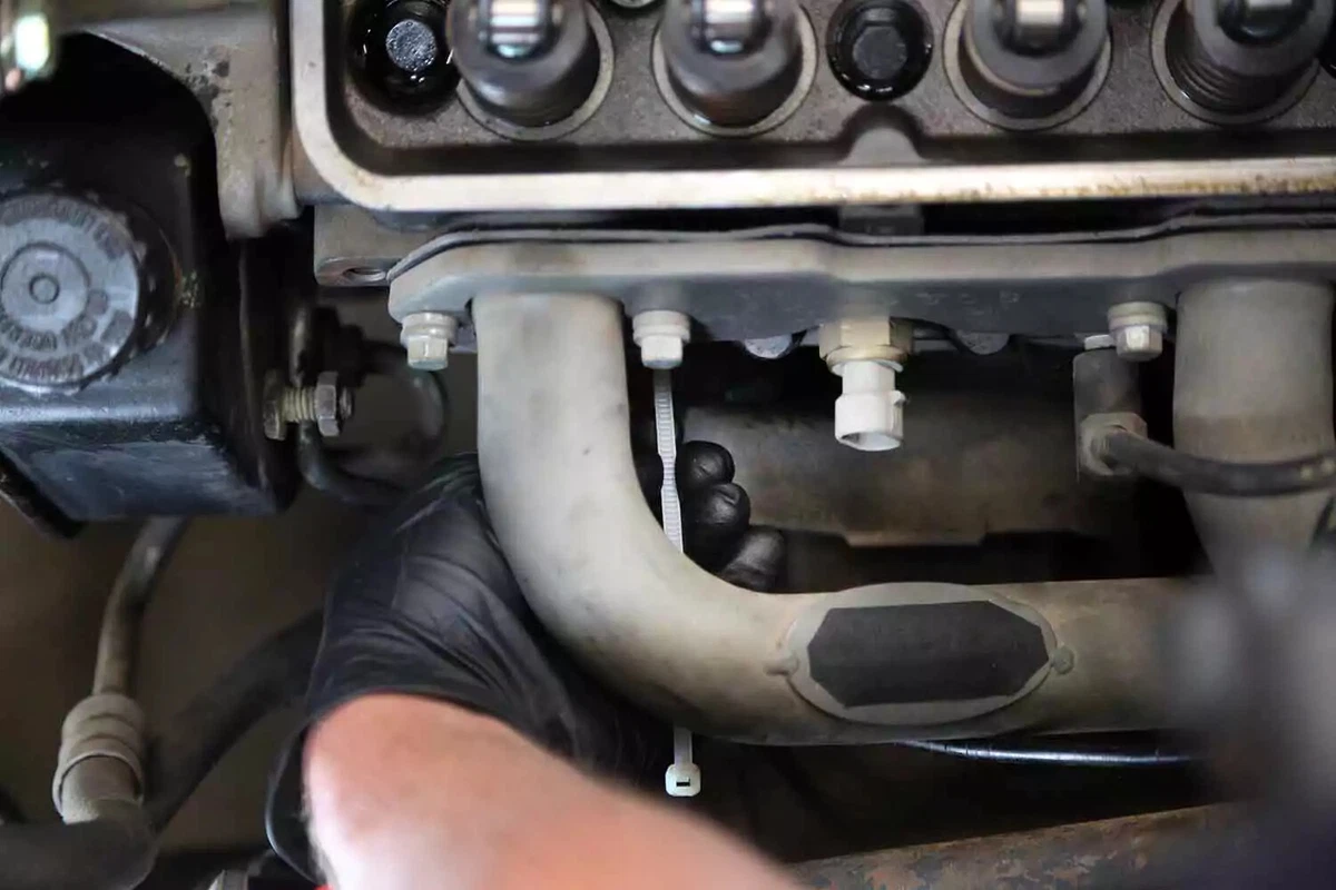 A mechanic probes the first cylinder’s spark plug hole with a zip tie to determine TDC.