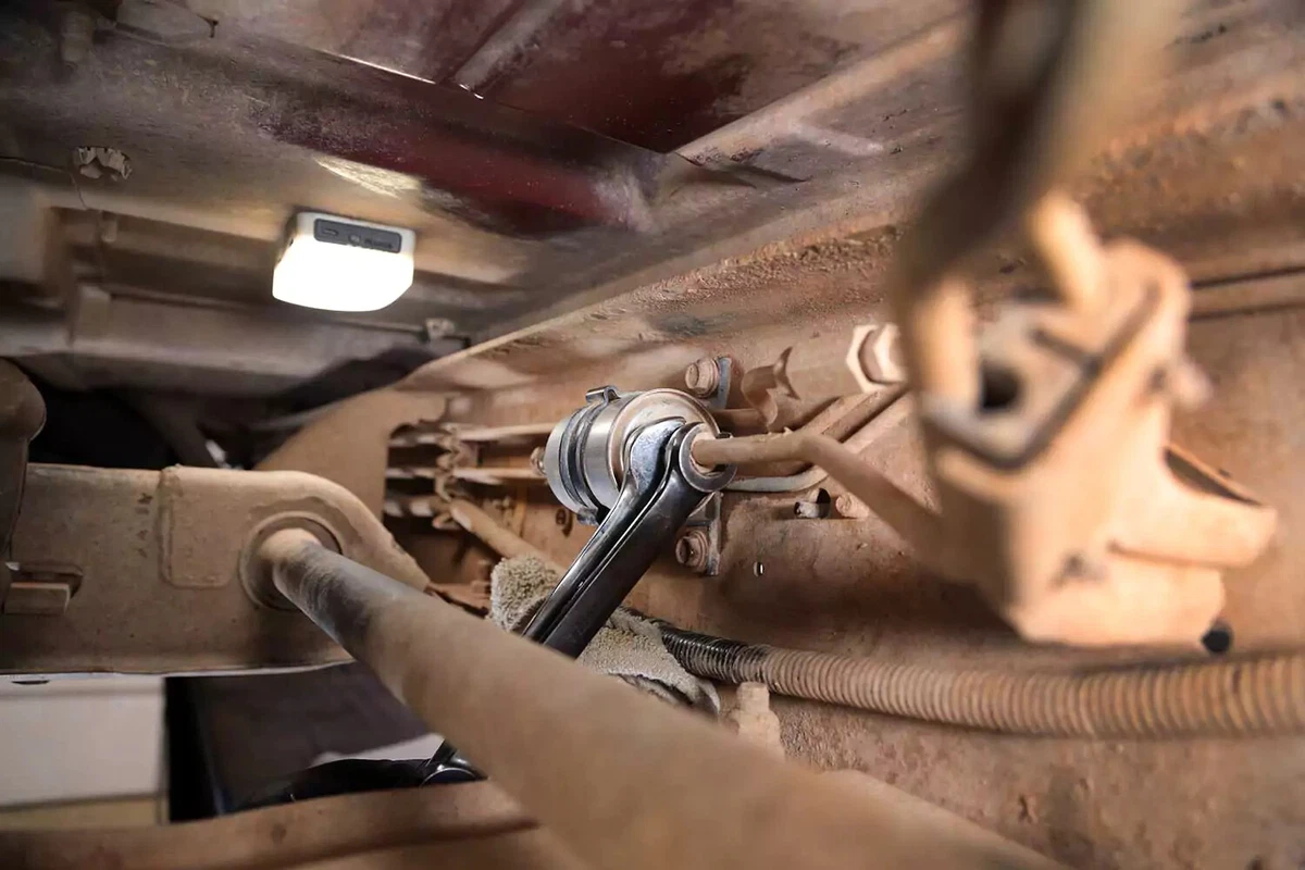 A mechanic loosens the second fuel filter fitting with a line wrench and an open-end wrench.