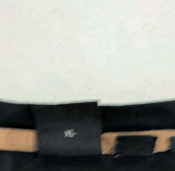 Black BOSS x Muhammad Ali T-shirt with brown leather patch, elastic waistband, and GOAT logo on white background.