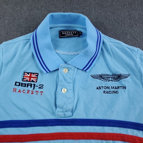 Light blue Hackett London polo shirt with navy trim, embroidered Aston Martin Racing logo, and Union Jack on chest.