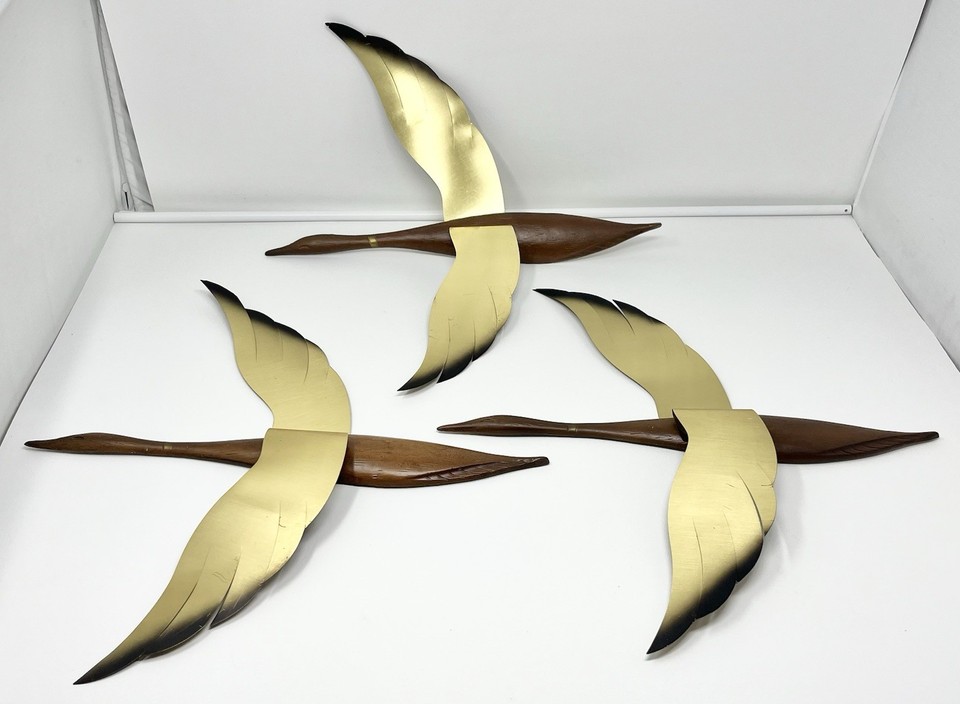 A trio of brass flying geese with faux wood-grain wings — peak 1960s atomic-era wall decor and an instant conversation piece.