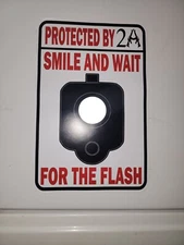 Protected by  2A Smile and Wait for the Flash Sign 12" x 8" with reflect barrel