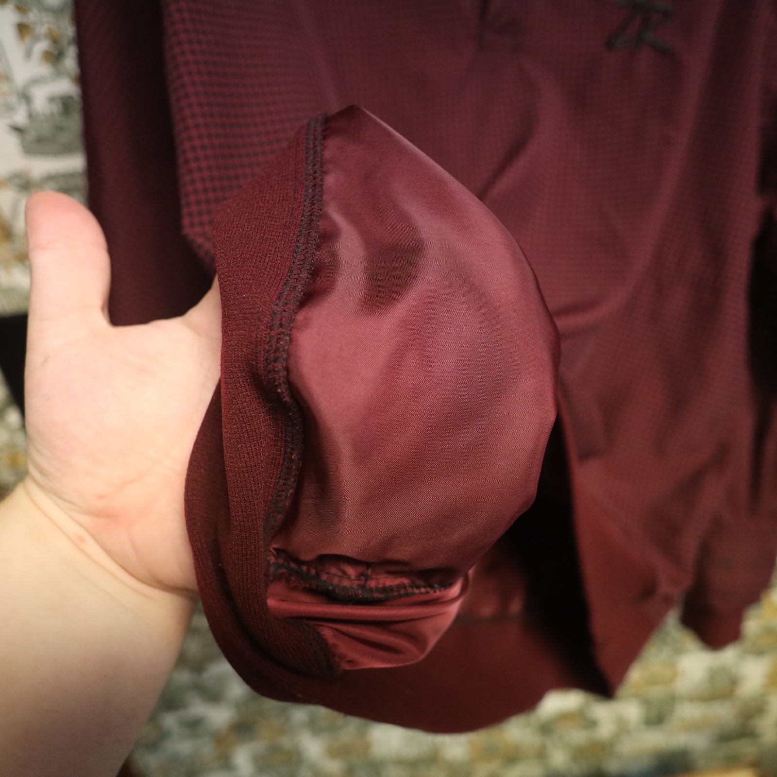 VTG Zero Restriction men’s golf jacket with maroon houndstooth fabric, black zipper, and visible stitched seams.