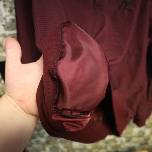 VTG Zero Restriction men’s golf jacket with maroon houndstooth fabric, black zipper, and visible stitched seams.