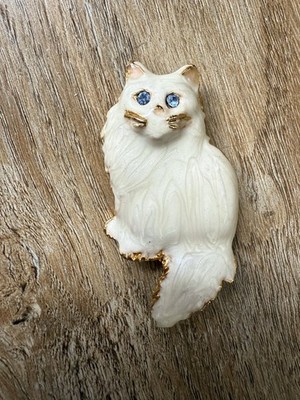 Vintage cat-shaped brooch, covered in beige enamel, with blue rhinestones.