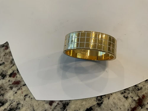 Bracciale Kate Spade oro con cerniera accenti smalto bianco inciso all'interno