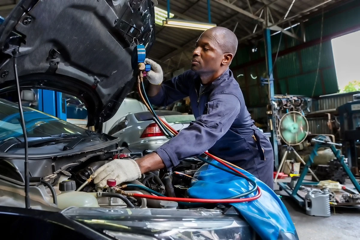 Auto mechanic fixing an air conditioner system