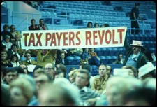 Foto: [Dos hombres sosteniendo pancarta que dice "Revuelta de los contribuyentes"]