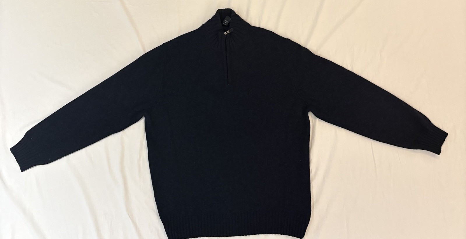 Navy wool-cashmere quarter-zip sweater laid flat on a white sheet.
