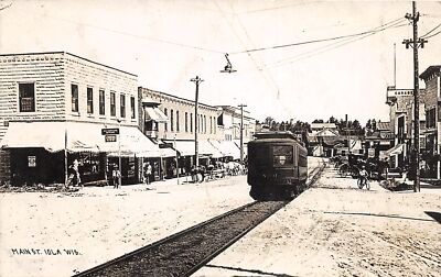 J47/ Iola Wisconsin RPPC Postcard c1910 Trolley Stores Main Street 259