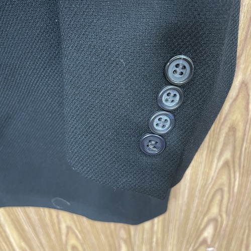 Black solid three-button blazer jacket with notch lapels, front flap pockets, and dark buttons on the seam.