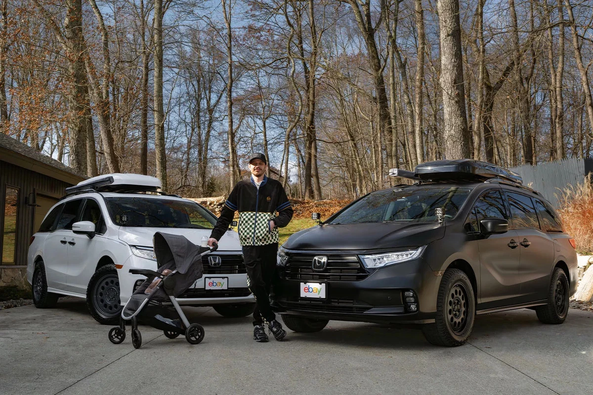 Actor and comedian Pete Davidson stands with a baby stroller between two modified minivans.