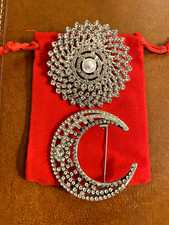 Pair of costume brooches: a crescent moon & a sunburst, in red draw-string pouch