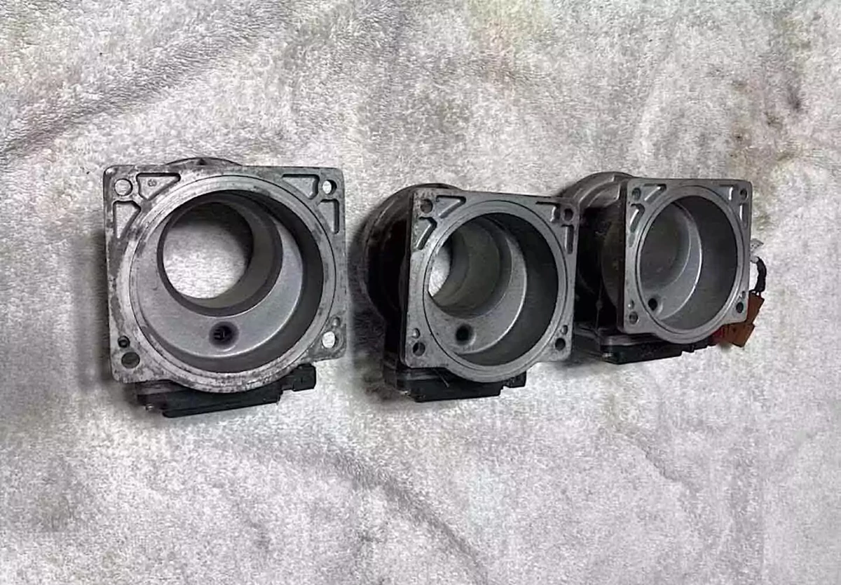 Three used OEM Nissan SR20DET mass air flow sensors displayed on a shop towel.