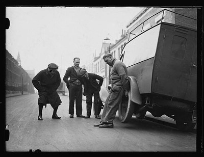 Men look on as another man lifts a truck in 1932 1930s Old Photo