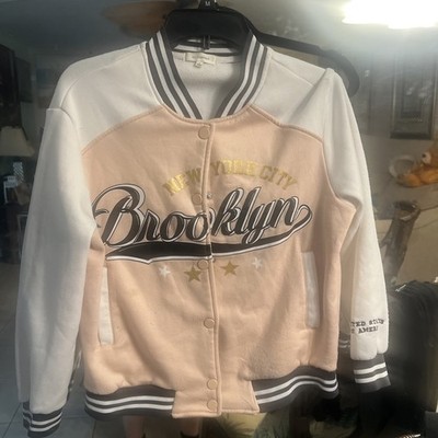 pink and white varsity jacket featuring a ''Brooklyn'' design. No Comment