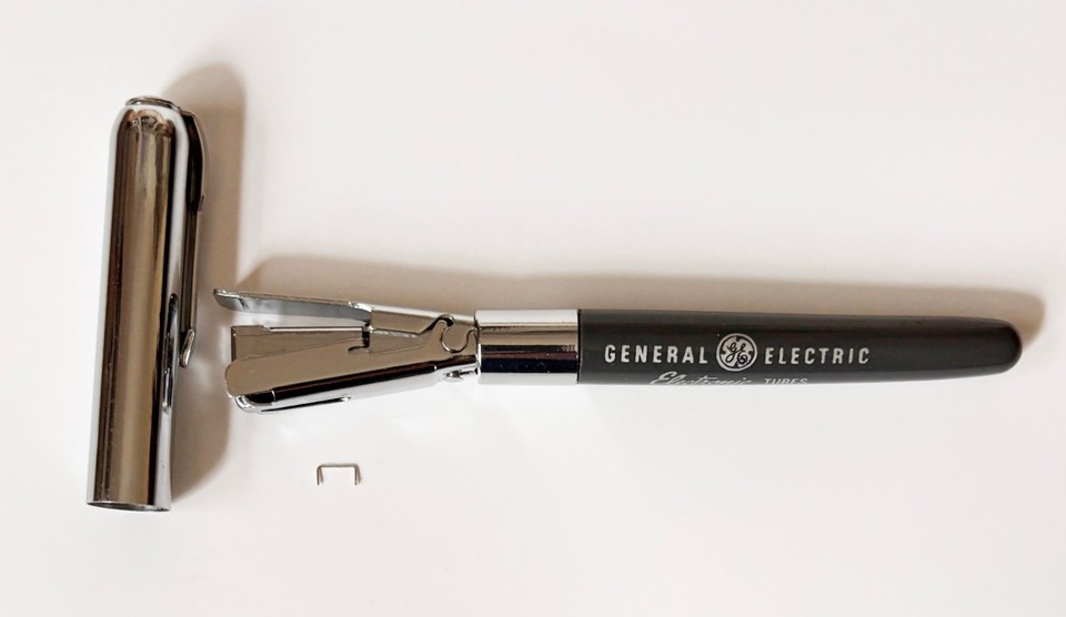 A General Electric vacuum tube–shaped promotional stapler — an actual functional stapler that looks like a piece of mid-century industrial art.
