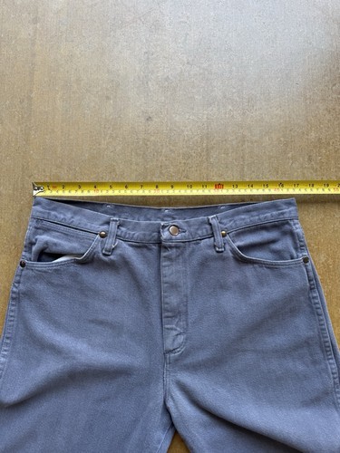 Gray VTG 90s Wrangler straight leg cowboy pants with five pockets, button closure, and yellow measuring tape across the waistband.