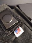 Black nylon IWB holster with metal clasp, two front pockets, and white USA flag patch on black fabric background.