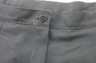 Black Jantzen women’s pants with front button closure, pleated detailing, and two front slash pockets on a dark fabric background.